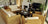 Salon accueillant avec canapé et fauteuils en rotin, table basse sombre et écran TV, ambiance naturelle et zen.