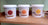 Three white paint buckets labeled “anachromie” with natural colors (rouge 304, orange 201, jaune 101) displayed on a wooden shel