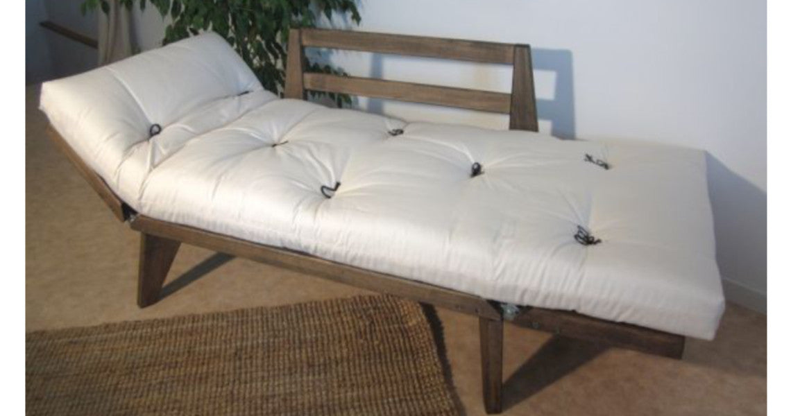 Divan LEO couchage 1 place: canapé-lit en bois avec coussinage blanc tufté et dossier à lattes, posé dans un salon. Position mér